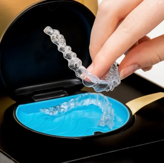 Invisalign Dentist Howell – patient holding a clear aligner at Riverpark Dental of Howell